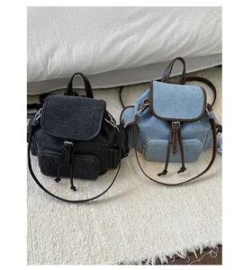 Dettaglio degli zaini in denim grigio e blu con rifiniture in pelle marrone e fibbie