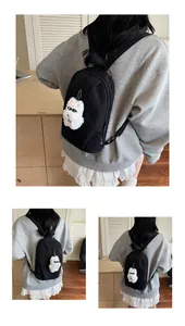 Dettaglio dello zaino in nylon nero con un portachiavi a forma di mostro di peluche