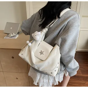 Detail der cremeweißen Ledertasche mit Sternschnalle und Wolkenanhänger im Lifestyle