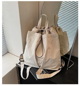 Détail macro du sac beige avec cordon, texture en nylon et étiquette de marque tissée