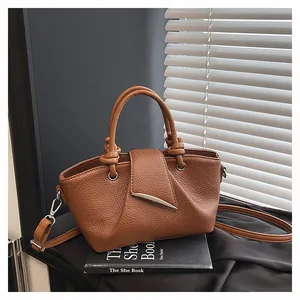 Dettaglio borsa in pelle martellata marrone con chiusura a mezzaluna e manici con nodo decorativo