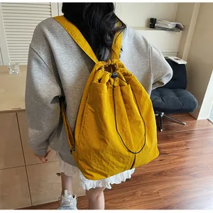 Détail d'un sac à dos jaune à cordon porté par un mannequin en nylon décontracté
