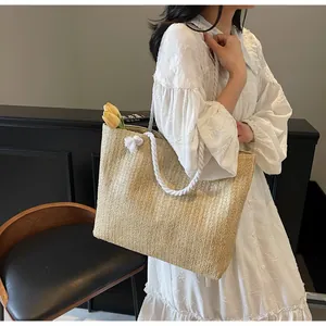 Detail of woven straw tote bag with white cotton rope handles and casual vertical texture