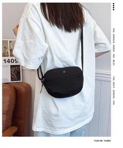 Detail of minimalist black shell bag with silver metallic logo and adjustable strap