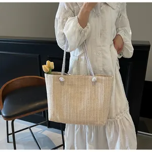Detailed texture of straw woven tote with knot handles held by a model in a white dress
