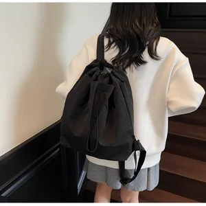 Détail d'un sac à dos noir à cordon montrant la texture nylon et la poche à rabat avant