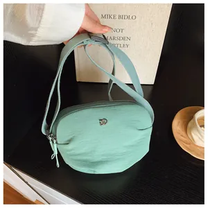 Detail of mint green shell bag featuring nylon texture and multi-zipper compartments
