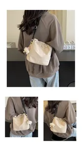 Détail du sac seau à cordon beige avec bandoulière noire et pendentif boule de peluche