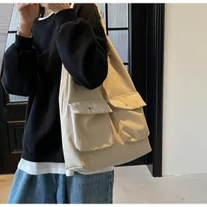 Makroansicht der beigefarbenen Canvas-Tasche mit zwei Vordertaschen und Metallknöpfen