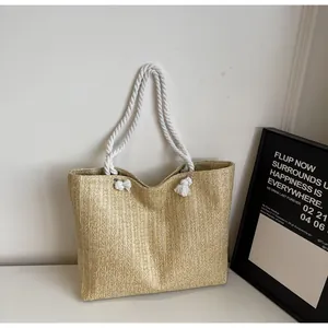 Detailed close-up of woven straw texture and white cotton rope handle on summer beach tote