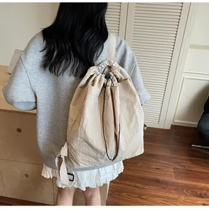 Sac à dos à cordon beige en tissu texturé porté par un modèle, vue de profil détaillée