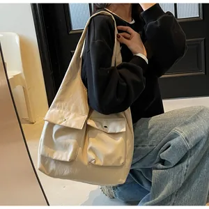 Detailaufnahme einer großen beigen Canvas-Einkaufstasche mit Vordertaschen am Freizeitoutfit