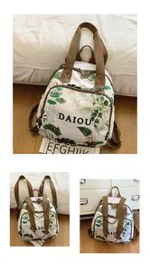 Close-up of white floral backpack with green leaf prints and brown woven straps