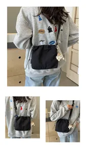 Détail du sac bandoulière noir avec étiquette KAKA et joli pendentif peluche monstre