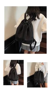 Détails du sac à dos noir à cordon montrant le tissu texturé et la poche avant ouverte