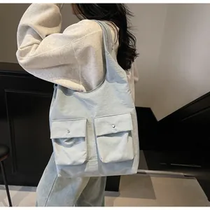 Detail der hellblauen Tragetasche mit aufgesetzten Taschen und Nylon-Textur