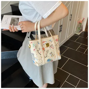 Detailansicht der beigen PU-Leder Handtasche mit bunten Graffiti-Prints und Goldbeschlägen