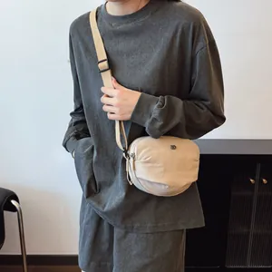 Minimalist beige shell crossbody bag with adjustable strap and small metal logo on front