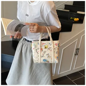 Detailaufnahme der Graffiti-Tasche aus weißem PU-Leder mit modischen Metallbeschlägen