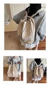 Gros plan sur le sac à dos beige à cordon en tissu texturé avec étiquette logo