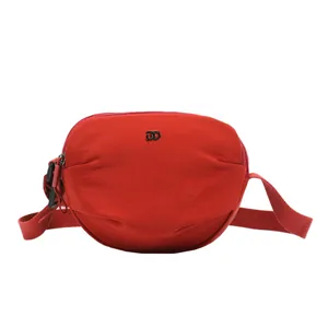 Minimalist red canvas shell-shaped crossbody bag with metal logo and adjustable strap