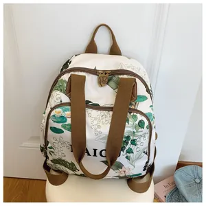 Detail of metal zipper pull with animal relief on white floral backpack with green print