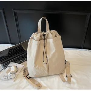 Détail d'un sac à dos en nylon beige avec cordon de serrage, poches avant et poignée