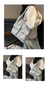 Detail der hellblauen Tragetasche mit zwei Vordertaschen und Metall-Druckknöpfen
