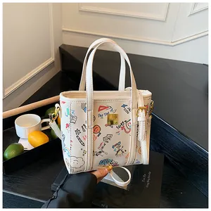Detail der weißen Graffiti-Tasche mit bunten Skizzen und goldenem Logo-Schild