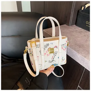 Nahaufnahme der weißen Graffiti-Beuteltasche mit goldenen Beschlägen und bunten Mustern