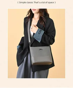 Detail view of a large grey bucket bag with a metal kangaroo logo and shoulder strap