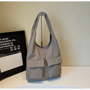 Detailansicht der grauen minimalistischen Tragetasche mit zwei Vordertaschen und Metallknöpfen