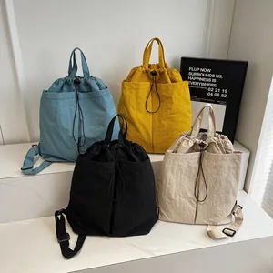 Sacs à dos en nylon minimalistes en bleu, jaune, noir et blanc sur un socle en marbre