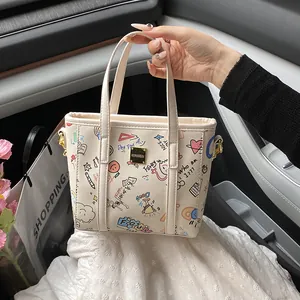 Cremefarbene Graffiti-Tasche mit bunten Skizzen und goldenem Logo im Autoinnenraum gezeigt