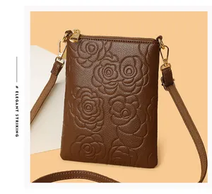 Detail view of embossed rose pattern on deep brown lychee grain leather crossbody bag