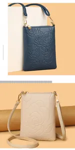 Detail of rose embossed crossbody bags in navy and cream white with gold zippers