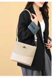 Detail of beige canvas and leather bucket bag with kangaroo logo on model shoulder