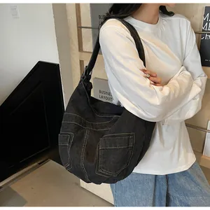Detail of black denim tote bag with cargo pockets and wide strap on Asian model