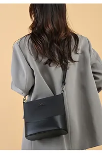 Detail of black bucket bag featuring textured leather contrast and metal logo