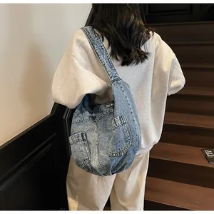 Macro detail of casual denim hobo bag featuring multiple functional pockets and vintage texture