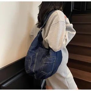 Detail of large denim crossbody bag showing yellow contrast stitching and side pockets
