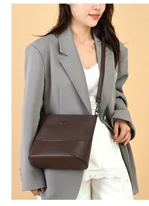 Detail of dark brown bucket bag with metal kangaroo logo and mixed fabric textures