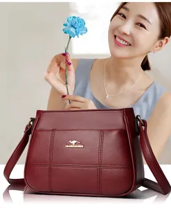 Close-up of wine red leather handbag with litchi texture and golden kangaroo logo