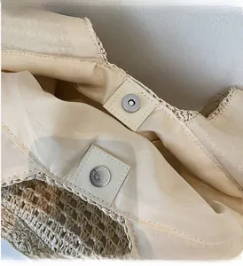 Detail of magnetic silver clasp and inner fabric lining of the beige woven tote bag