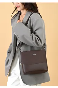 Detail showing deep brown textured bucket bag with silver kangaroo logo on grey blazer