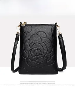 Detail of black camellia embossed crossbody phone bag with gold zipper and pebble leather
