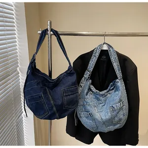 Detail of denim crossbody bags in dark and light blue with stitched pockets on metal stand
