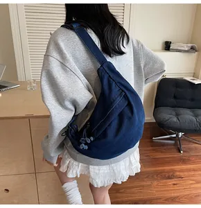 Detail view of the deep blue crescent denim shoulder bag shown on a model's side back