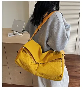Detail of a yellow large-capacity nylon crossbody bag worn on shoulder in a casual setting