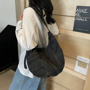Black denim crescent crossbody bag with contrast stitching and dual front pockets